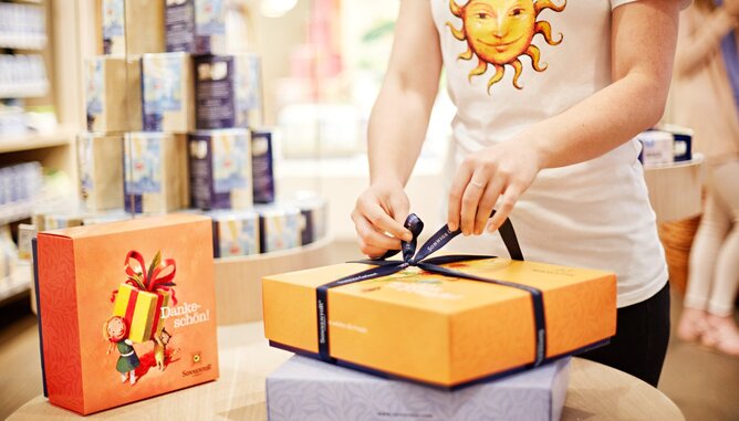 Nachhaltige Geschenke | © SONNENTOR Auf dem Foto sieht man eine Sonnentor Mitarbeiterin beim Einpacken eines Sonnentor Geschenkkartons. | © SONNENTOR